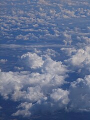 Majestic clouds seen from an airplane window during a clear day over the landscape below