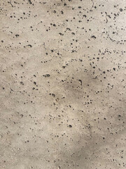 Heavily pitted concrete surface texture with dark spots, showcasing industrial grunge material for abstract backgrounds, urban design concepts, and rough architectural cladding