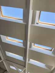 Multiple skylight windows installed in a contemporary sloped ceiling, showcasing modern interior architecture, natural light design, and bright attic space for residential and commercial concepts