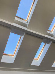 Multiple skylight windows installed in a contemporary sloped ceiling, showcasing modern interior architecture, natural light design, and bright attic space for residential and commercial concepts