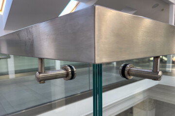 Close-up of a modern stainless steel railing corner on a glass balustrade, emphasizing seamless metalwork, contemporary design, and polished architectural details for commercial and luxury interiors.