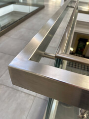 Close-up of a modern stainless steel railing corner on a glass balustrade, emphasizing seamless metalwork, contemporary design, and polished architectural details for commercial and luxury interiors.