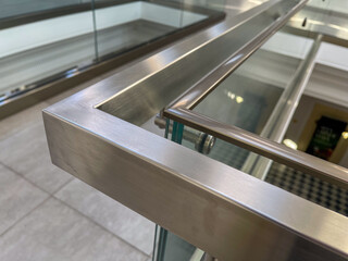 Close-up of a modern stainless steel railing corner on a glass balustrade, emphasizing seamless metalwork, contemporary design, and polished architectural details for commercial and luxury interiors.