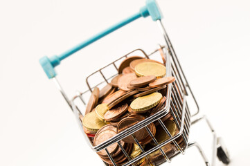 Dynamic Coin Haul: Angled Shot of a Shopping Cart Tilted with a Large Pile of Euro Coin Currency.