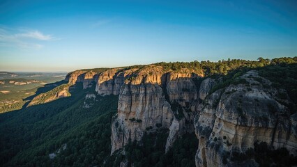 Cliffs and lush greenery in a canyon landscape under a clear blue sky during daytime.