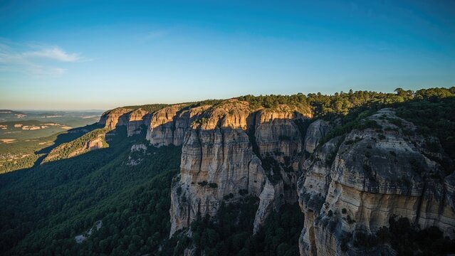 Cliffs and lush greenery in a canyon landscape under a clear blue sky during daytime.