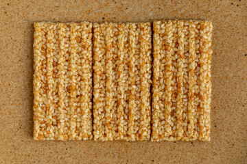 Close-up view of three sesame seed candy bars on a yellow background.