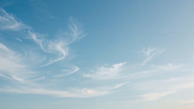 Clear blue sky with wispy clouds and soft sunlight, peaceful and calm atmosphere.