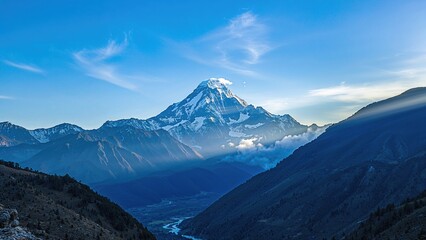 Fototapeta premium Mountain landscape with a prominent snow-capped peak, blue sky, and surrounding valleys. Nature and wilderness, scenic view. The concept of mountains and natural landscapes.