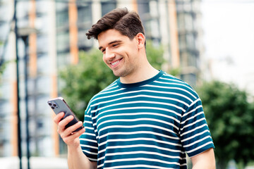 Young man enjoying daylight in urban park setting with modern buildings in background showcasing casual fashion