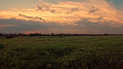 Sunset sky over green meadow, camera panning. Beautiful natural landscape. Outdoor travel, tourism, adventure photography. Sunrise over serene natural landscape with clouds in sky green grassy field