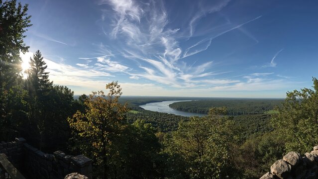 A panoramic view of the landscape with river, forest, and blue sky with clouds. - Powered by Adobe