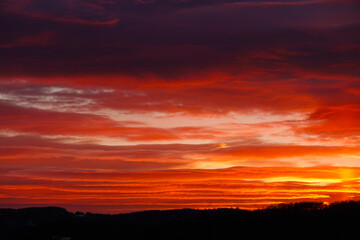 SILHOUETTE: Winter sunset paints the sky in vivid red and orange tones. Colorful layered clouds...