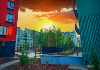 Bright sunset casts warm colors over contemporary apartment buildings. Pathways in peaceful...