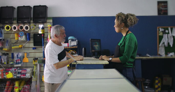 Shopkeeper and elderly customer having a conversation at the counter in a hardware store, fostering connection and excellent customer service