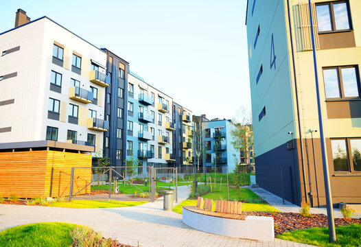 Modern residential building with Private Backyard courtyard. New condo complex structure features multiple balconies, windows. Contemporary living in urban environment. Enclosed Apartment courtyard.