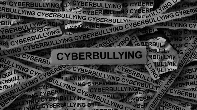 Strips of newspaper with the words Cyberbullying typed on them. Black and white. Close up.