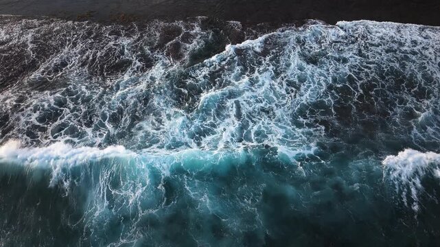Stunning slow motion footage of powerful blue waves impacting dark rocky coast with spectacular water spray