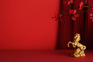 Luxurious background for Chinese New Year with a golden rearing horse statue and a red pleated curtain and plum blossom. Theme for Year of the Horse prosperity and fortune