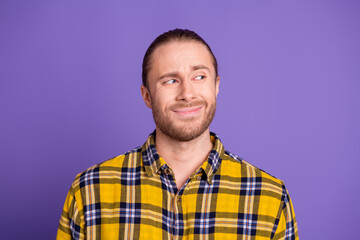 Obraz premium Young handsome man in a yellow plaid shirt smiles softly against a purple background for lifestyle fashion advertising and promotional imagery