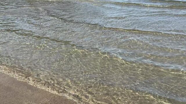 Gentle sea waves rolling onto a sandy beach.