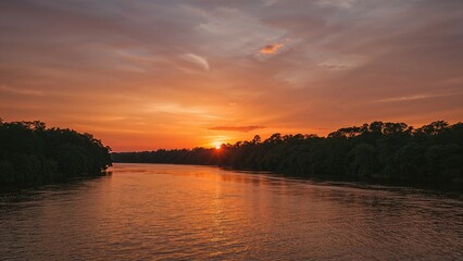 Sunset over a river with trees on both sides and orange sky. Nature scenery, evening landscape, tranquil water, and sunset view.