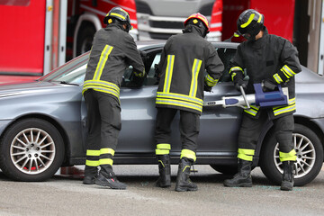 firefighters working with the hydraulic cutter to cut the cars sheet metal after the road accident