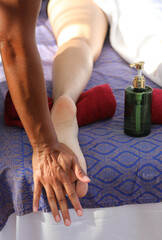 massage therapists hand massaging the foot sole of the woman lying on the luxury spa bed during the relaxation session