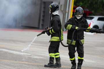 firefighters in uniform and protective helmet with the fire hose during the emergency