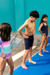Obraz premium Children doing warm up exercises before swimming lesson