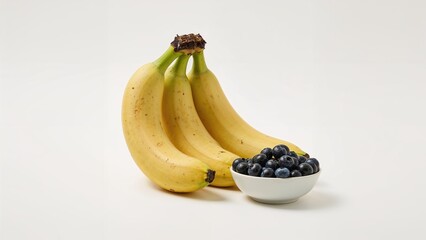 Three yellow bananas with brown spots and a bunch of blueberries in a white bowl on a plain white background
