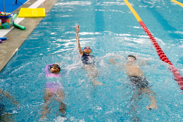 Children learning different swimming techniques in the pool