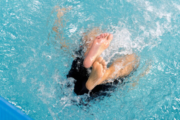 Children learning swimming skills by kicking feet in water