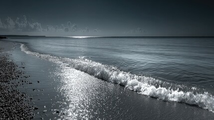 Ocean waves gently crash on the sandy beach under a cloudy sky.