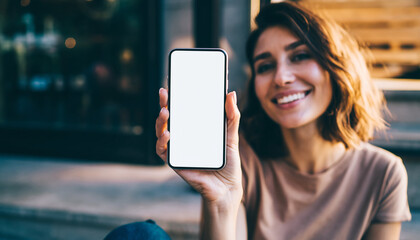 A woman cheerfully displaying a blank smartphone screen