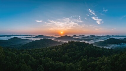 Obraz premium Sunrise over mountainous forests with mist and clouds. Natural landscape and scenery. The beauty of nature and peaceful environment.