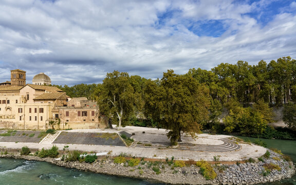 Rome, Italy, boat-shaped Tiber Island (Insula Tiberina). Scenic riverside view featuring historic architecture, lush greenery, and a serene waterway, creating a tranquil atmosphere