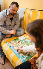 Happy father and child playing board game at home - happiness and family concept.
