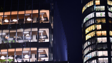 Modern office building in city center illuminated at night. Rows of lit windows against the architectural grid of a modern facade.