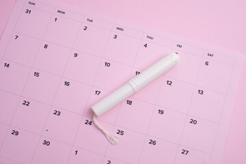 Menstrual сycle tracking: tampon on a pink calendar highlighting women's health