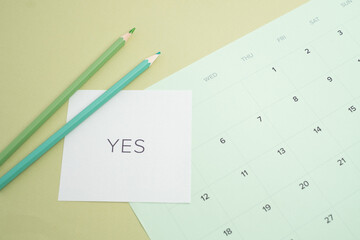 Affirmative decision: the word 'YES' on a calendar with pencils for planning and commitment
