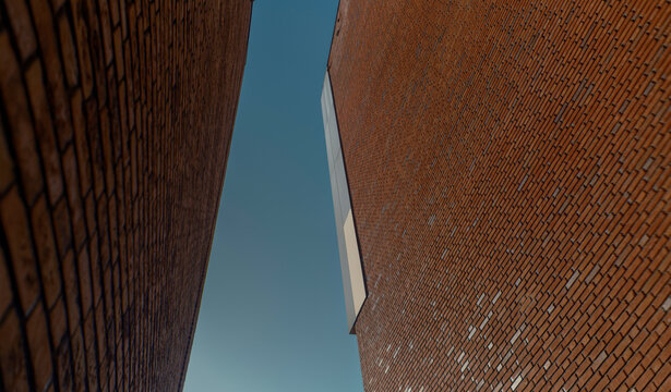Abstract angular composition of brown brick building facades meeting against blue sky (this image was made with an anamorphic lens)