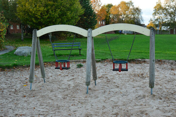 Playground Swings in Autumn Park with Sandpit and Trees