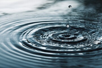 Gentle water droplets create calming ripples on serene surface, reflecting soft hues and evoking tranquility in a peacefulNature-focused environment. Ideal for relaxation and mindfulness projects