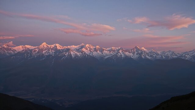 Snow-capped mountains at dawn with pink and purple sky, mountain range landscape. Nature and scenic view. The image captures the majestic beauty of the mountains during sunrise.