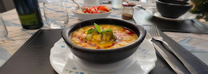 Plato de porotos granados. Comida chilena acompañada de tomates frescos y de albahaca