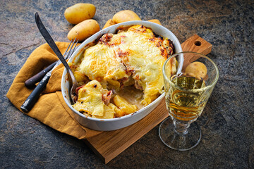 Artisan homemade oven baked tartiflette wih potato and reblochon cheese served as close-up in a casserole dish