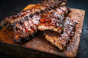 Barbecue smoked hot spicy pork spareribs St Louis cut with curry rub and BBQ sauce on wooden cutting board