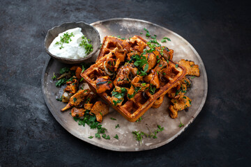 Fresh baked homemade Belgian Brussels waffles with pan roasted chanterelle mushrooms served as close-up on a rustic design plate