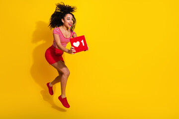 Cheerful woman holding a social media like icon sign, joyful expression, yellow background, promoting digital engagement